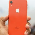 Smartphone iPhone XR de color naranja sujetado por un hombre