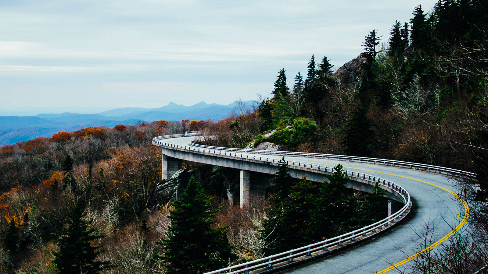Carretera en curva entre las montañas llenas de árboles.